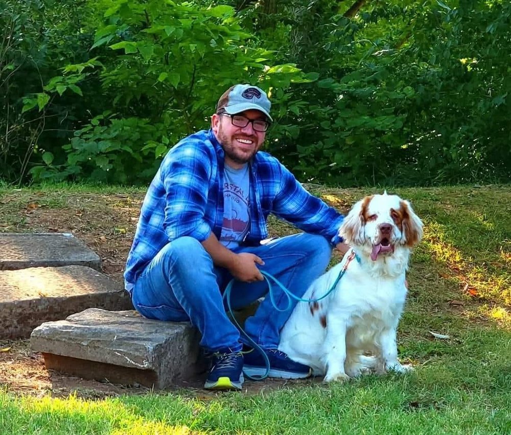 Ben sitting on a step beside a spaniel on a lead